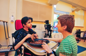 A child, in a wheelchair, participating in a sensory experience with an SEND carer.