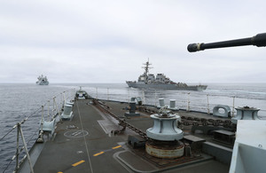Image depicts a ship's gun on a cloudy day.