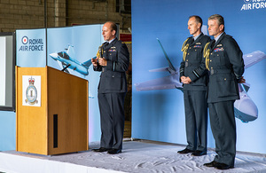 Air Chief Marshal Mike Wigston stands with two deputies in uniform on a platform.
