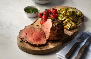 An image of a cooked beef steak fillet with vegetables on a wooden board.