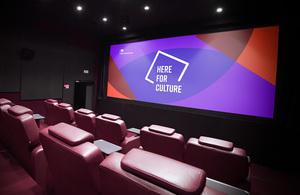 A cinema auditorium with a 'Here for Culture' graphic displayed on the screen