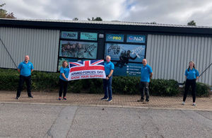 Staff of the Diving Centre standing outside with the Armed Forces Covenant flag.