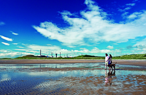 A family walks on the beach, with Sellafield - in Copeland - in the background