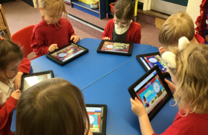Young school pupils around a desk using iPads.