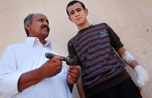 Mohamed pictured with his father Abdul, and the tail-fin of the grenade that cost him his left hand. Image: Sean Sutton/MAG