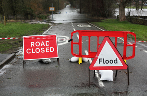 flood warning sign in front of flooded road