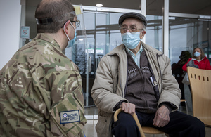 Image depicts a soldier and elderly gentleman sitting, speaking.