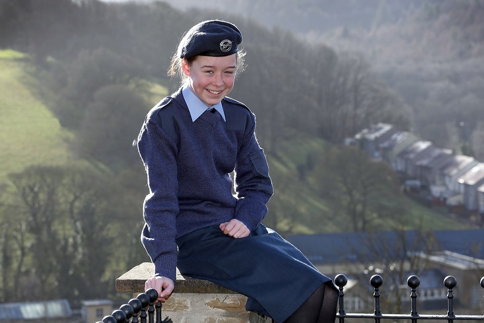 Air Cadet Mya Larder pictured wearing her uniform sitting on a wall smiling directly at the camera.
