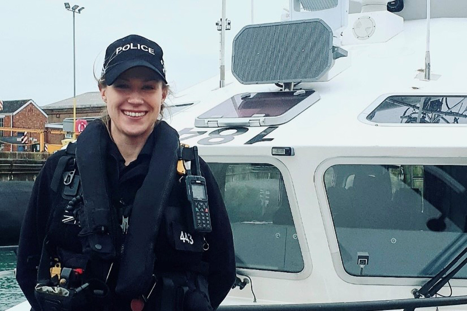 Kirsty in her MDP uniform stands outside a police boat.