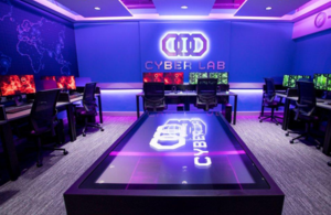 Inside the cyber operations lab showing desks and computer screens, with purple ambience lighting.