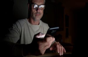 Photo showing man with glasses looking at phone with concern