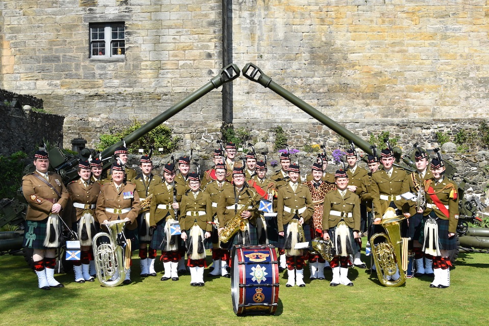 The whole band dressed in full uniform with instruments smiling at the camera. 