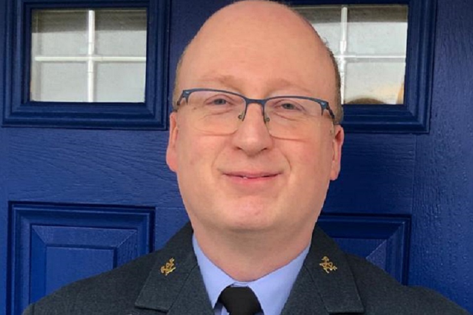 Close up portrait of Squadron Leader Paul Mathieson standing in front of a blue front door. 
