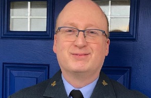 Close up portrait of Squadron Leader Paul Mathieson standing in front of a blue front door.