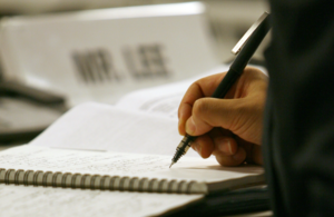 Close-up of person writing in notebook.