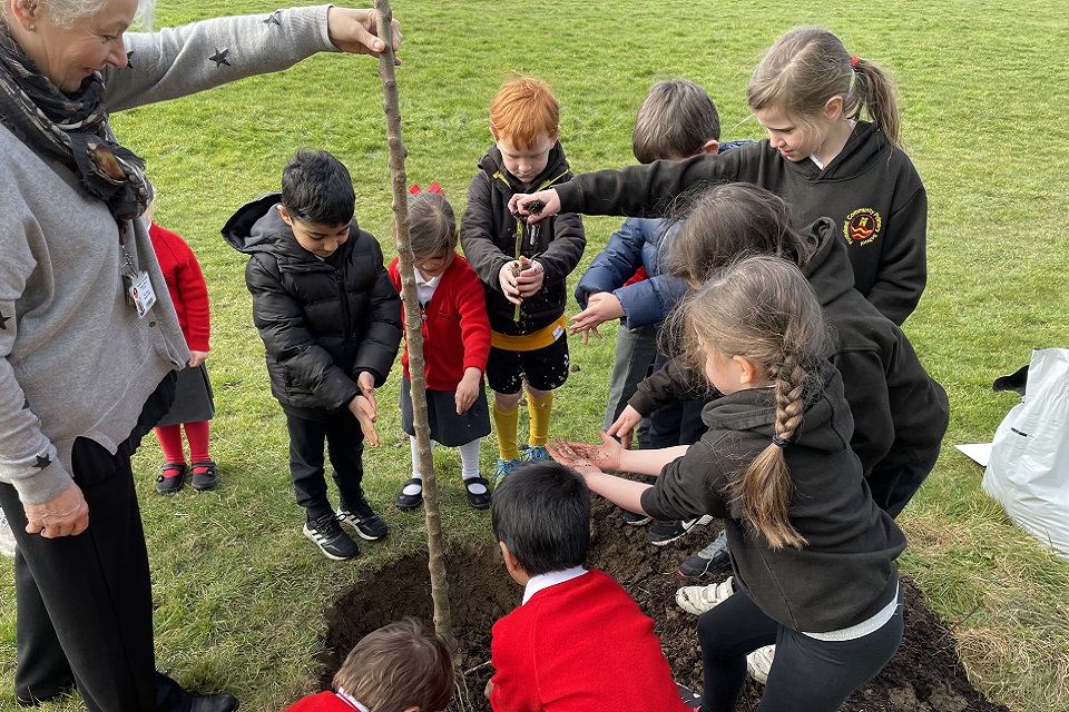 The images shows the school pupils planting a tree in the ground 