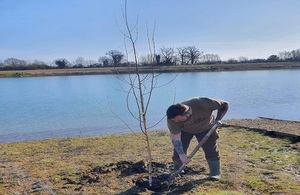 A member from one of the fisheries planting a tree.