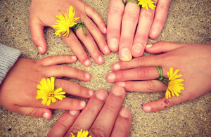 A circle of hands including adults and children with dandelions on their fingers
