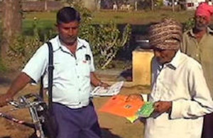 A postman delivers leaflets on eggplant borer control to a farmer