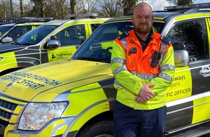 Highways England traffic officer Dave Harford standing near Traffic Officer vehicles in hi-vis clothing