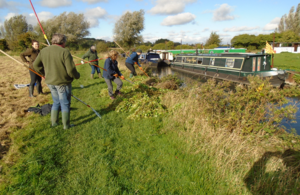A group of Cam Valley Forum volunteers on a riverbank preparing to tackle floating pennywort on the river Cam.