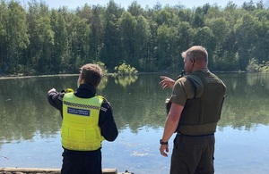 Image shows a Northumbria Police officer on the left and Environment Agency officer on the right, overlooking a lake from behind
