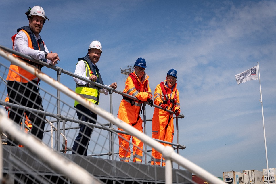 Image shows 4 people wearing high visibility clothing and hard hats leaning against metal railings