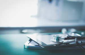 Picture of a mobile device and a stethoscope on a table.