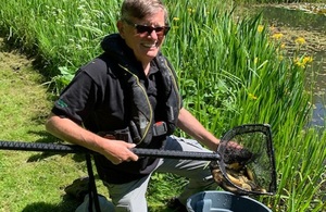Image shows the Environment Agency's Paul Slater releasing the crucian carp into Thirleycote Lakes.