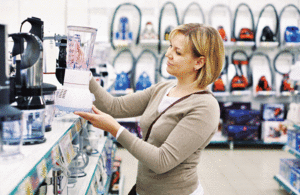 A woman examines a food mixer in a shop.