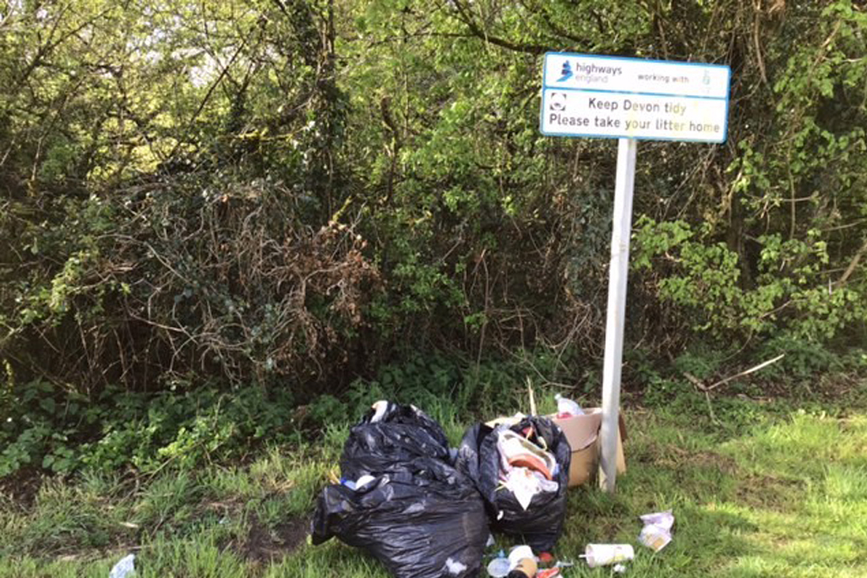 Litter left underneath a Highways England ‘Keep Devon tidy’ sign in a layby