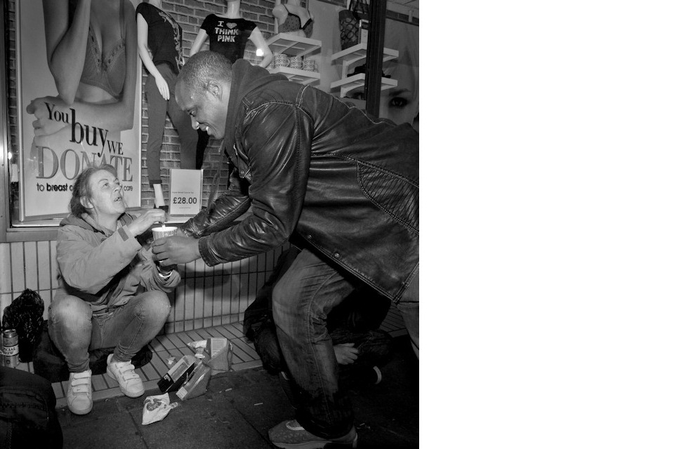 A man giving food to a homeless woman