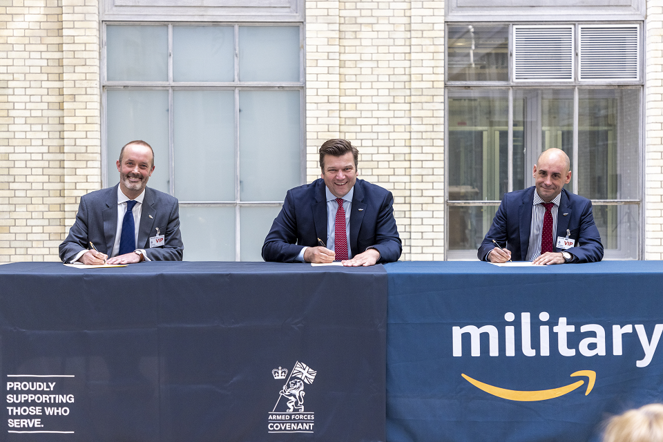 Minister for the Armed Forces, James Heappey, with John Boumphrey, VP Country Manager UK for Amazon and Chris Hayman, UK Public Sector General Manager at Amazon Web Services sit together at a table and re-sign the Armed Forces Covenant