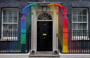 Image of a string art installation on the Downing Street arch in the Pride flag colours.