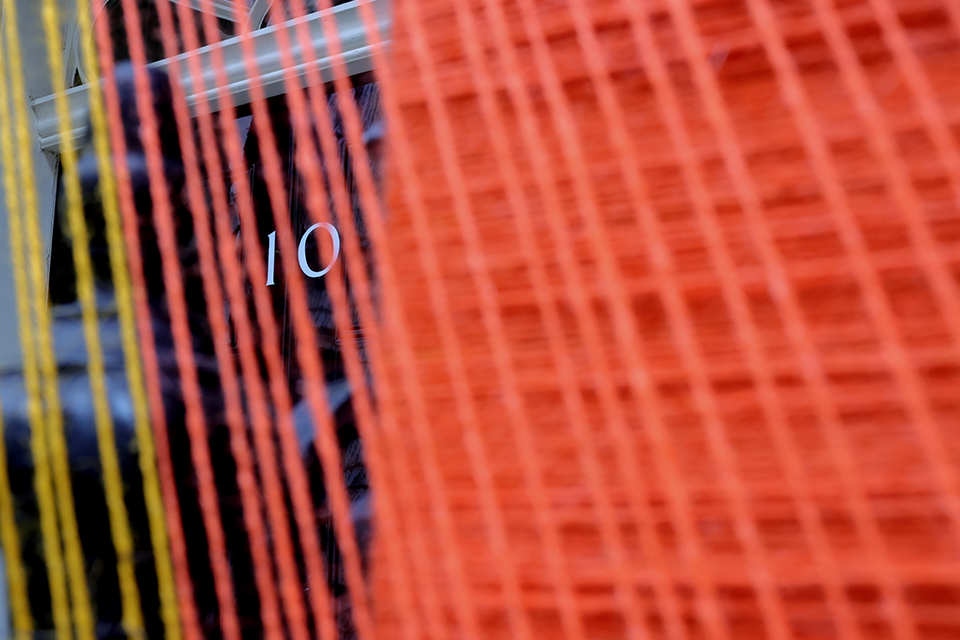 Close up image of the No10 door through the orange string of the Pride art installation.