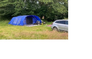 A large blue tent pitched in a grassy field