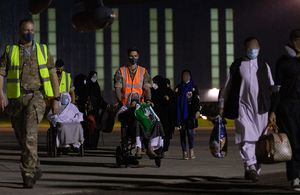 A member of the RAF escorts Afghan refugees at RAF Brize Norton