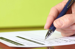 Hand with pen signing an application form