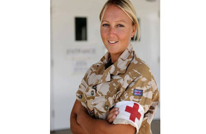 Rebecca Warren dressed in army reserve uniform smiles to camera and stands with arms folded.