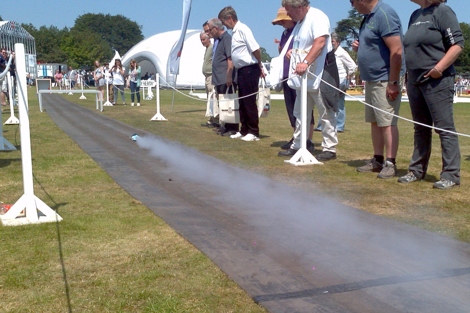 Spectators watch a rocket-propelled car on a track