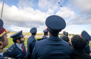 Группа официальных лиц смотрит на два самолета Hawk, пролетающие над головой