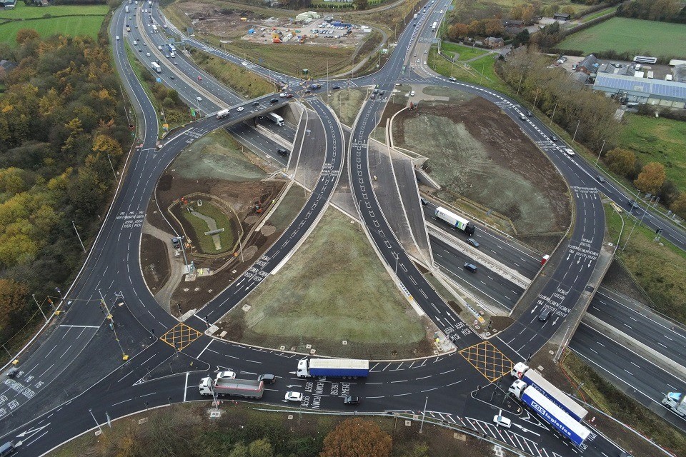 Снимок с воздуха: водители проезжают по мосту и проезжают новые перекрестки с круговым движением.