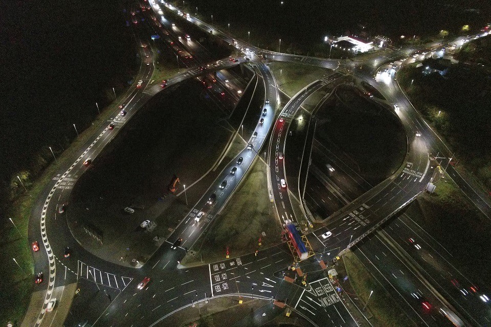 Снимок с воздуха: водители проезжают по мосту и проезжают новые перекрестки в ночное время.
