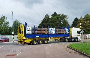 Lorry carrying metal pipework is travelling along the road