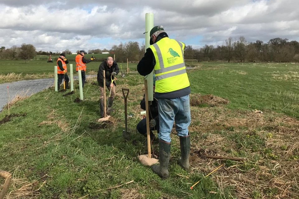 People planting trees. One is wearing a high vis saying River Waveney Trust.