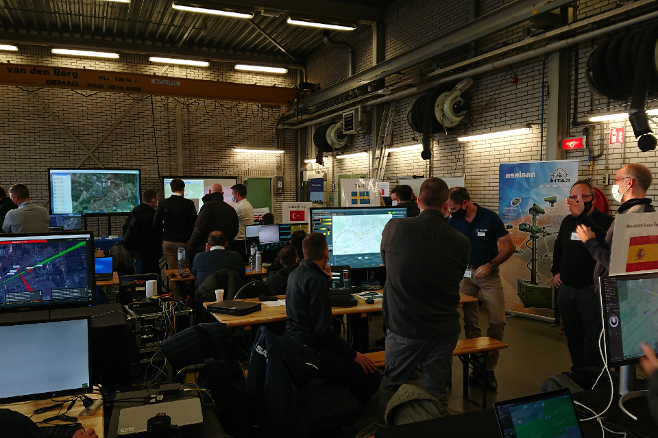 People gathered round multiple computer screens with mapping information