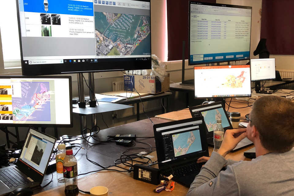 People gathered round multiple computer screens with mapping information