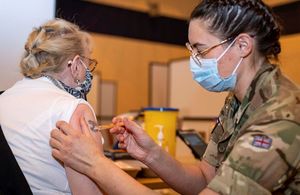 A member of the Armed forces vaccinates a member of the public.