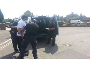 Immigration Enforcement officers lead a man away following a visit to commercial premises in London
