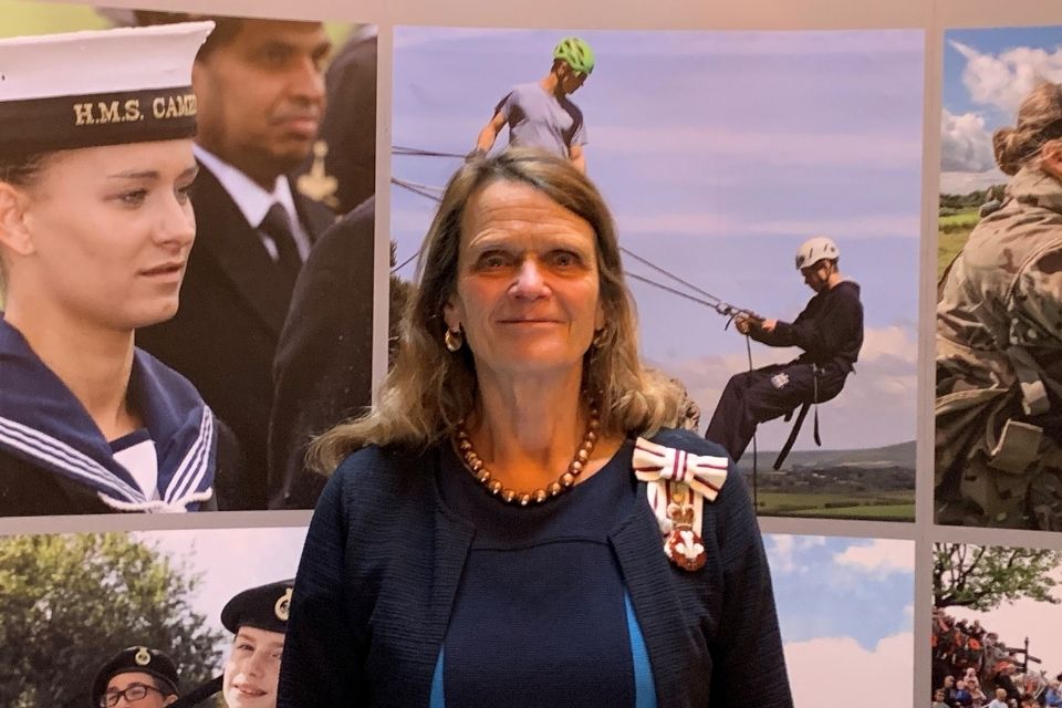 Lady smiling against military backdrop.
